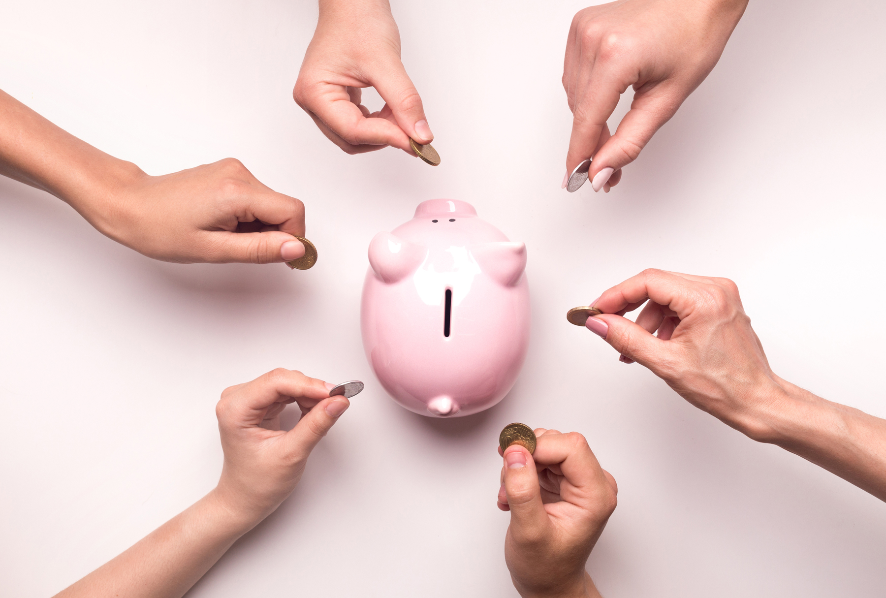 circle of hands holding coins with a piggybank in the middle
